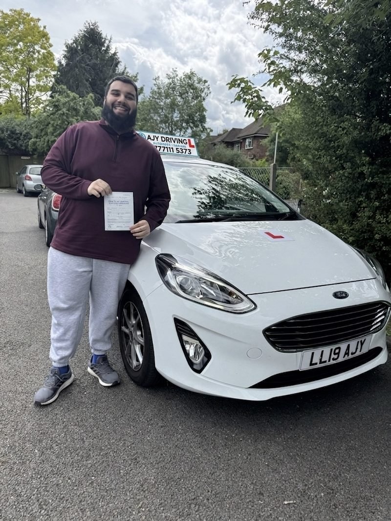 A learner standing proudly with their driving test pass certificate