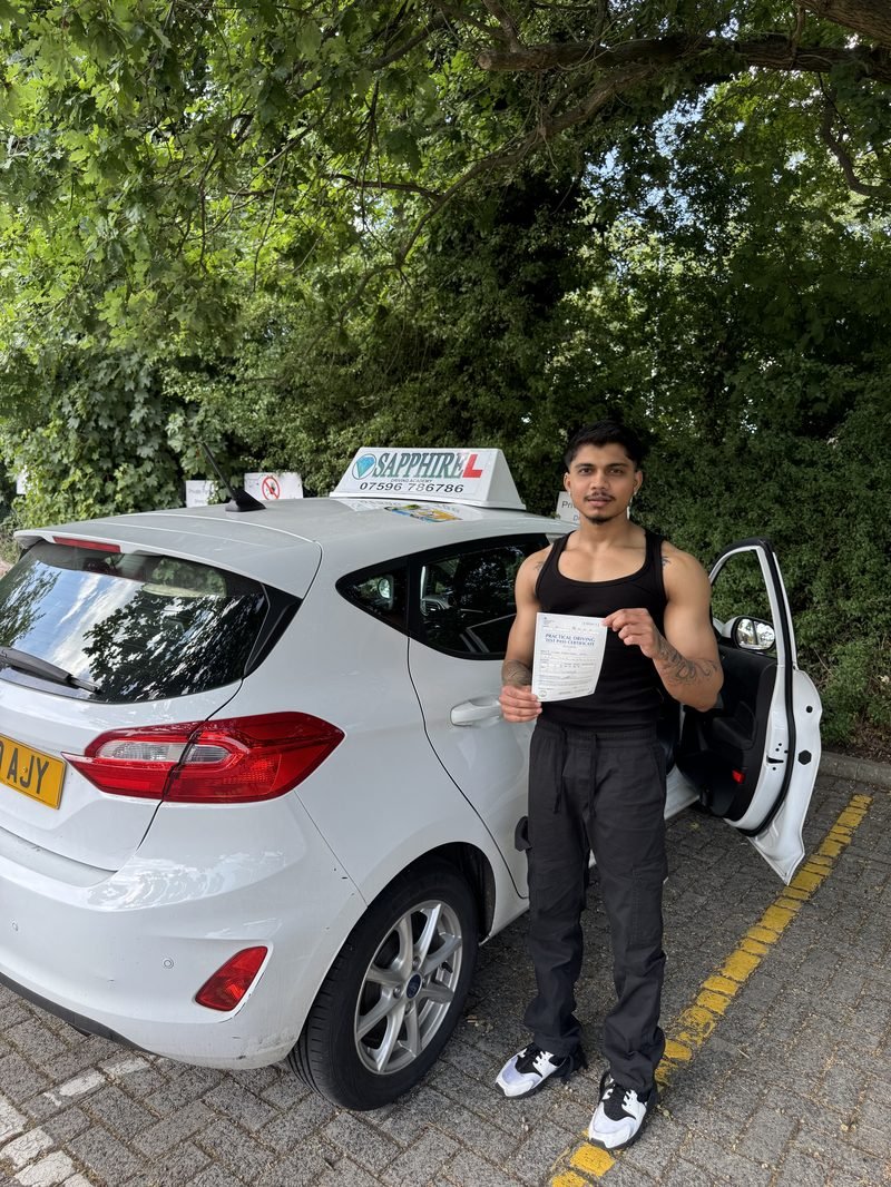 A learner standing proudly with their driving test pass certificate